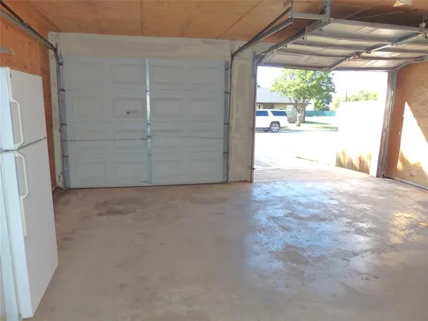 a view of empty room with window and refrigerator