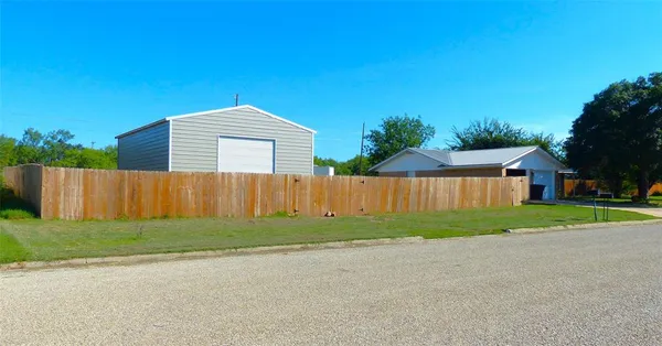 a view of backyard of house with wooden fence