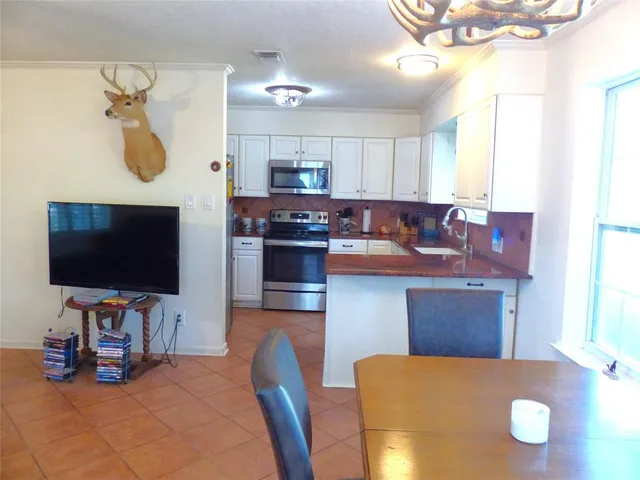 a kitchen with stainless steel appliances granite countertop a stove and a view of living room
