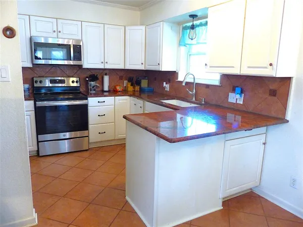 a kitchen with stainless steel appliances granite countertop a stove a sink and a microwave
