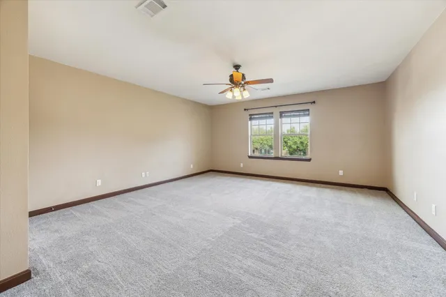 an empty room with windows and chandelier fan
