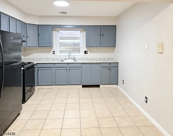 a kitchen with granite countertop a sink a stove a refrigerator and white cabinets