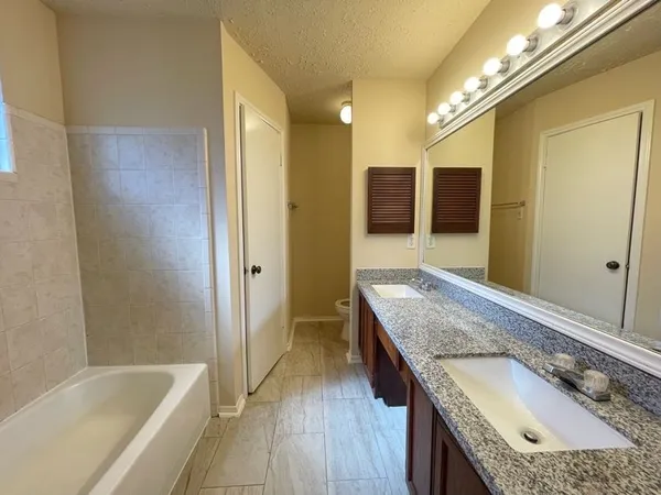 a bathroom with a granite countertop tub a sink and a large mirror
