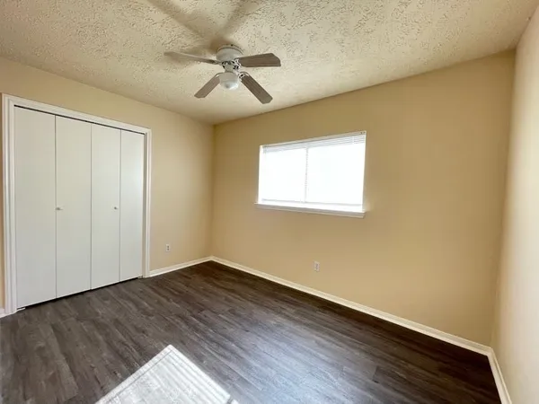an empty room with wooden floor fan and windows