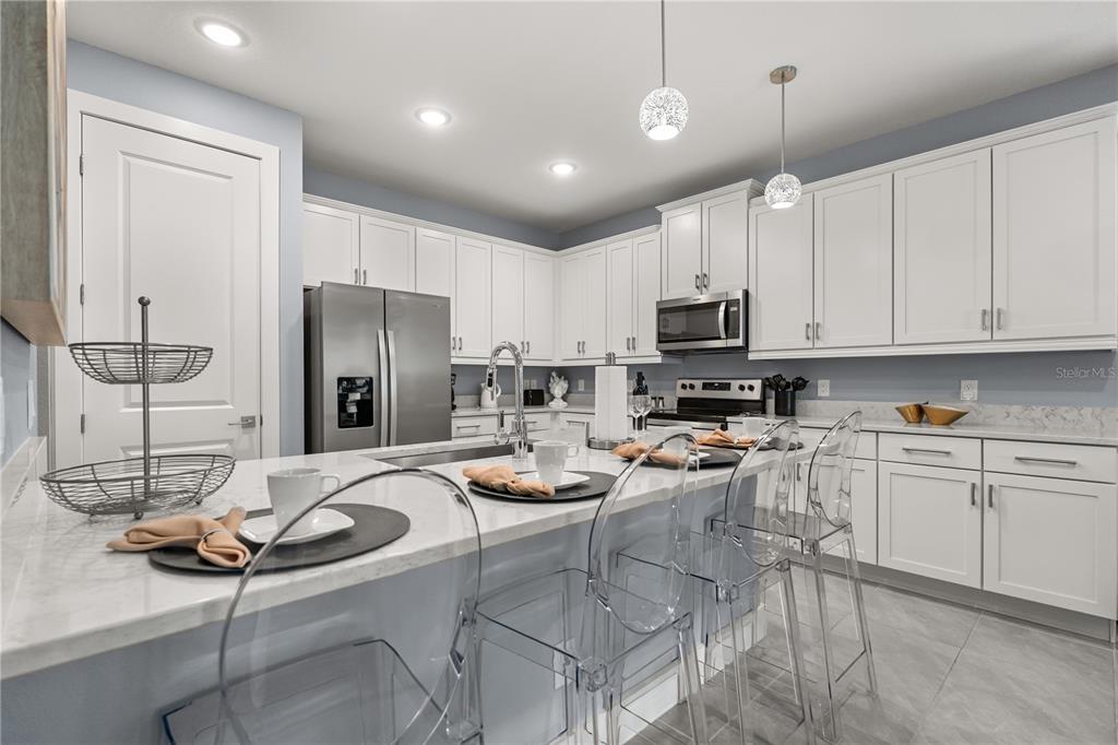 7456 Gathering Drive Reunion, FL 34747 - Photo 6 of 49 a kitchen with a refrigerator a stove a sink and a dining table with chairs