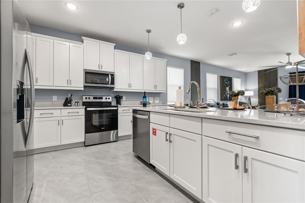7456 Gathering Drive Reunion, FL 34747 - Photo 7 of 49 a kitchen with kitchen island granite countertop white cabinets white stainless steel appliances with a sink and dishwasher