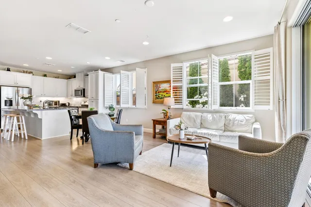 a living room with couches and kitchen view with wooden floor