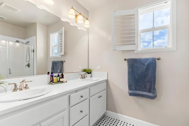 a bathroom with double vanity and a mirror