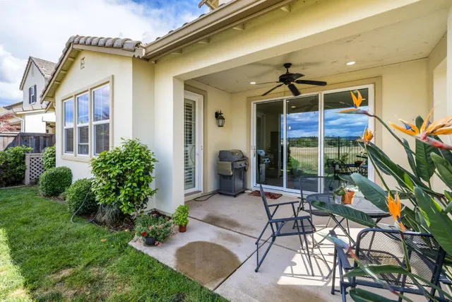 a view of a patio with table and chairs potted plants and floor to ceiling window