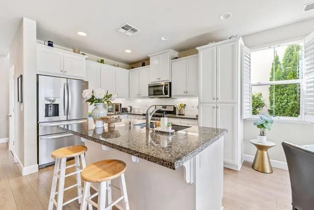 a kitchen with granite countertop stainless steel appliances a refrigerator a stove a dining table and chairs