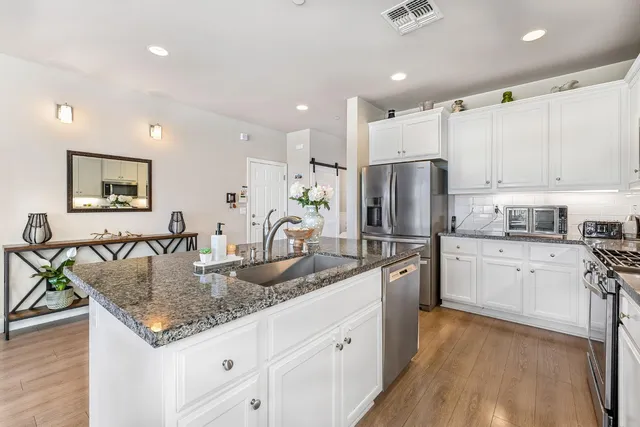 a kitchen with stainless steel appliances granite countertop a sink refrigerator and cabinets