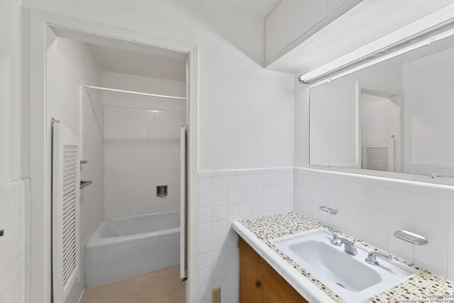 a bathroom with a granite countertop sink a mirror and a bathtub