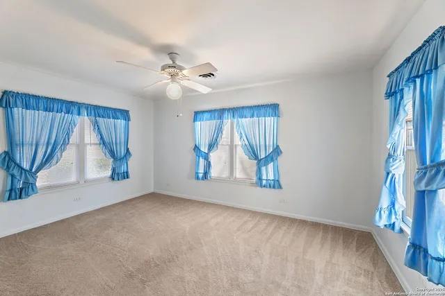 an empty room with windows and fan