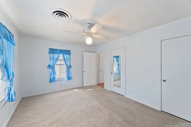 an empty room with windows and fan