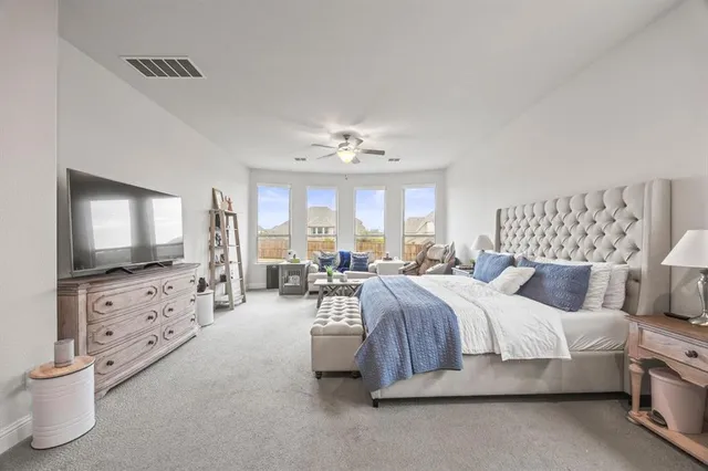 a spacious bedroom with a bed and a flat screen tv