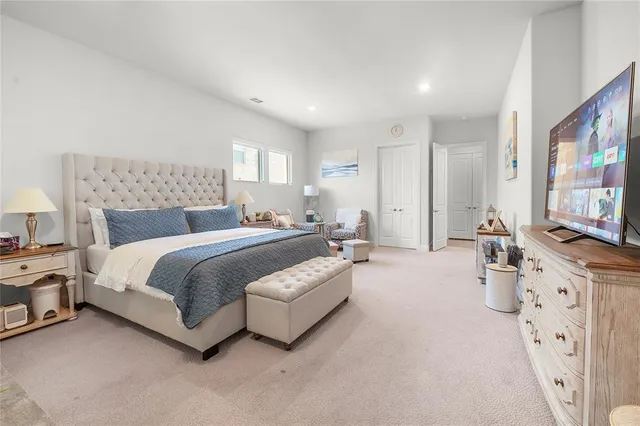 a spacious bedroom with a bed and a flat screen television