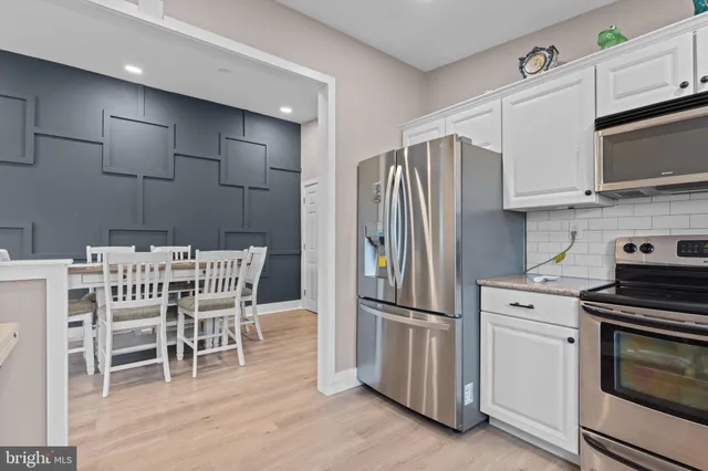 a kitchen with stainless steel appliances a refrigerator stove microwave and white cabinets