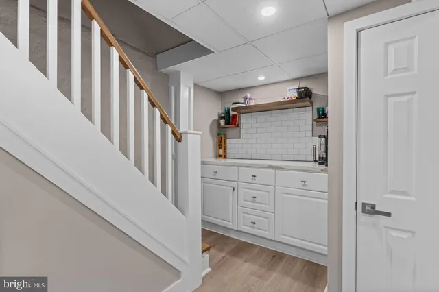 a hallway with white cabinets and stairs