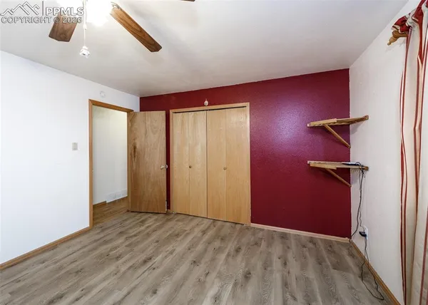 an empty room with closet and a ceiling fan