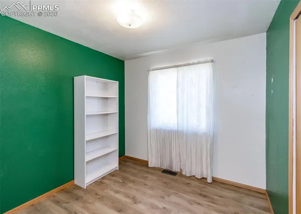 a view of an empty room with closet and wooden floor