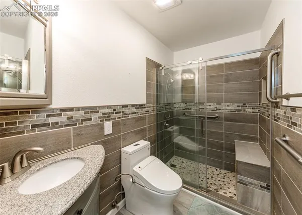 a bathroom with a granite countertop toilet a sink and a mirror