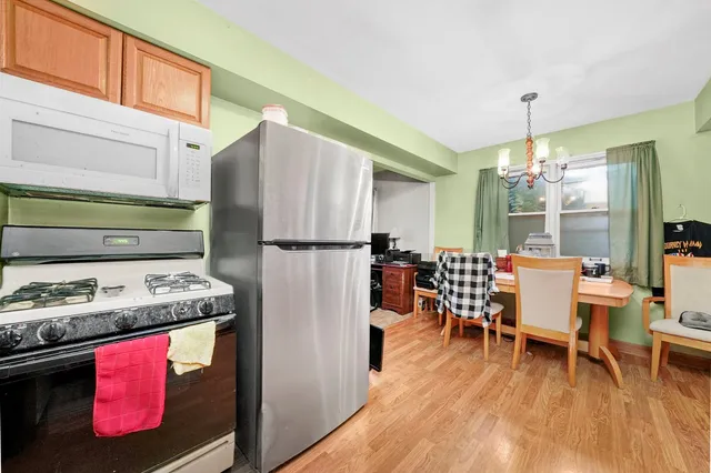 a kitchen with stainless steel appliances granite countertop a stove refrigerator a dining table and chairs with wooden floor