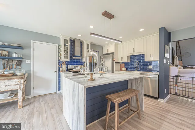 a large kitchen with kitchen island a sink dishwasher a stove and white cabinets with wooden floor