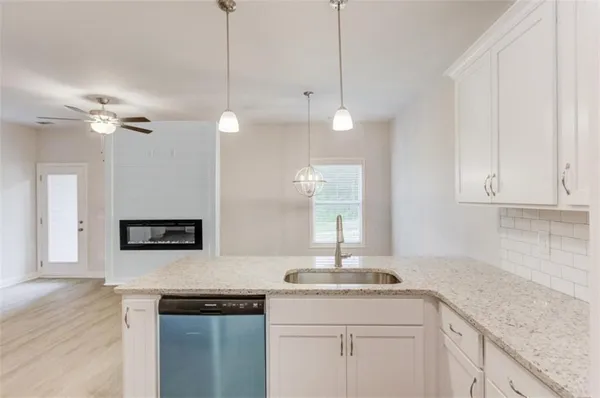 a kitchen with stainless steel appliances granite countertop a sink a stove and white cabinets with wooden floor