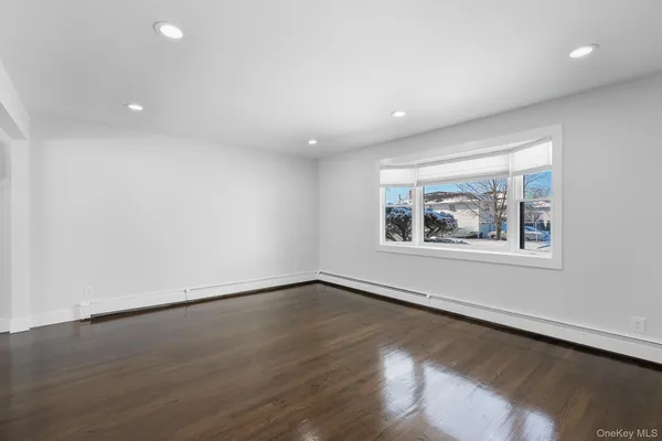 an empty room with wooden floor and window