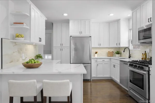 a kitchen with stainless steel appliances a white table chairs and a refrigerator