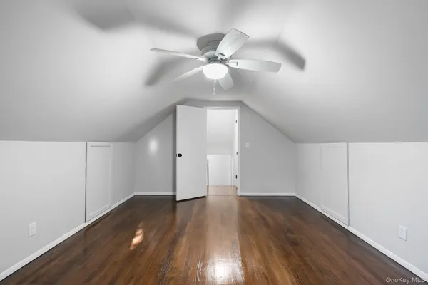 a view of an empty room with wooden floor and a ceiling fan