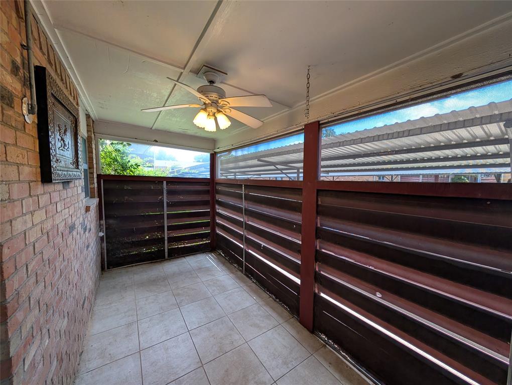 4715 Skillman Street, Unit A Dallas, TX 75206 - Photo 13 of 28 Covered outdoor patio featuring light-toned tile flooring, a ceiling fan with integrated lighting, brick wall construction, and slatted privacy screening
