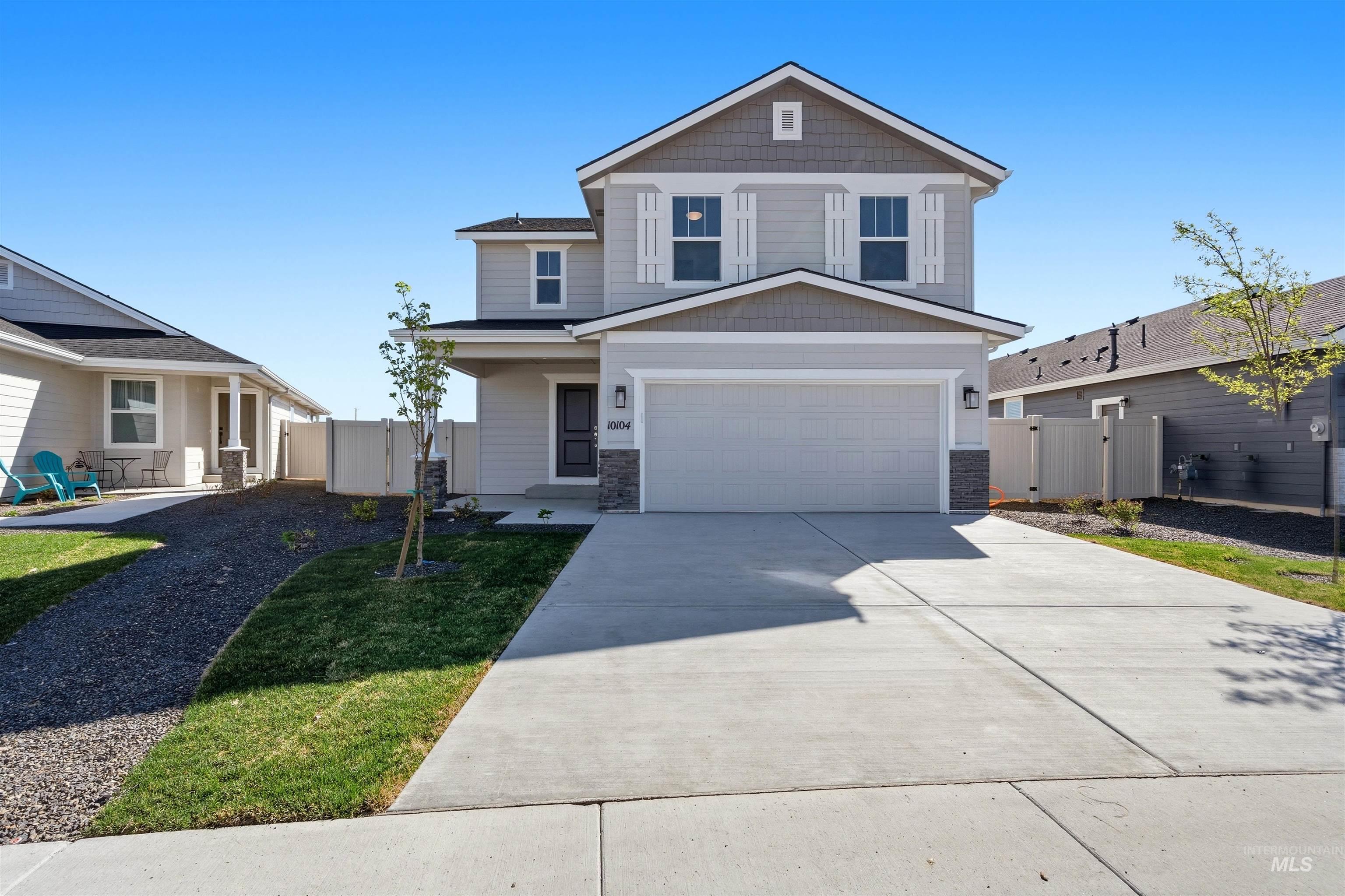 View of front of property with board and batten siding, a garage, driveway, and stone siding