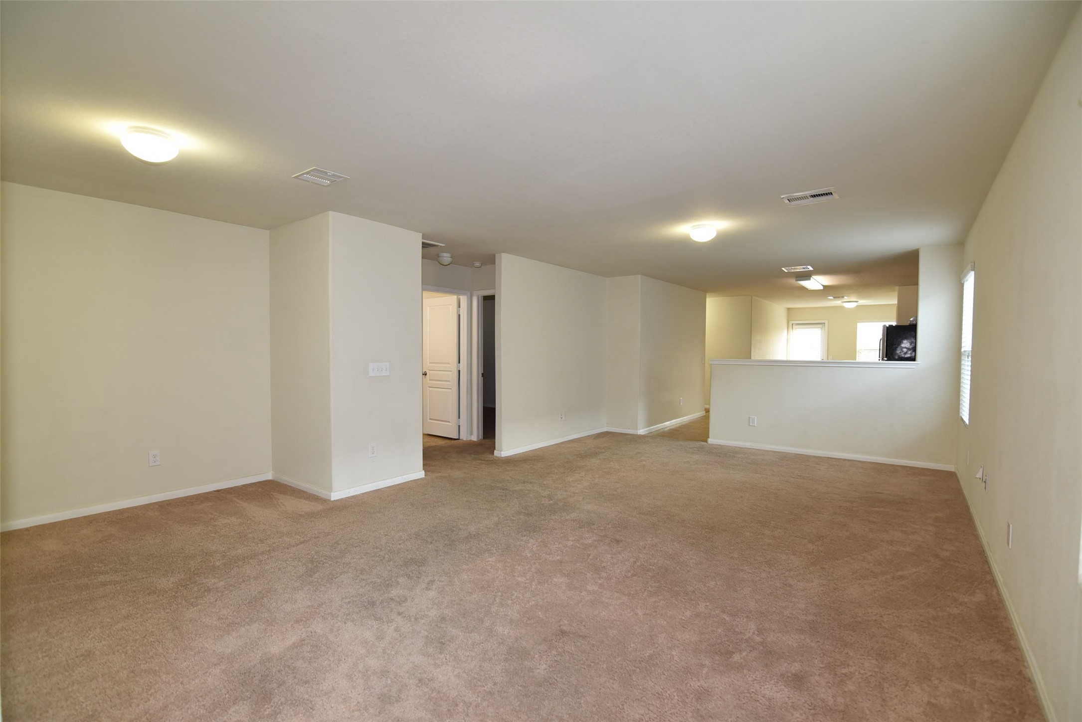 a view of an empty room and a kitchen