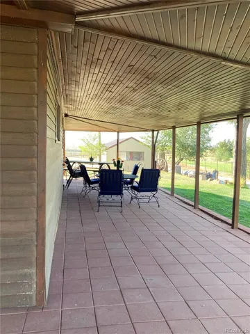 a view of a patio with table and chairs potted plants with floor to ceiling window
