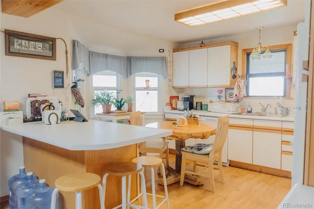 a kitchen with a dining table chairs sink and white cabinets