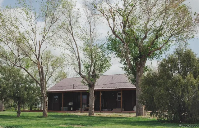 a front view of a house with a garden and trees