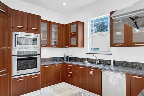 a kitchen with stainless steel appliances kitchen island granite countertop a table chairs in it and wooden floors