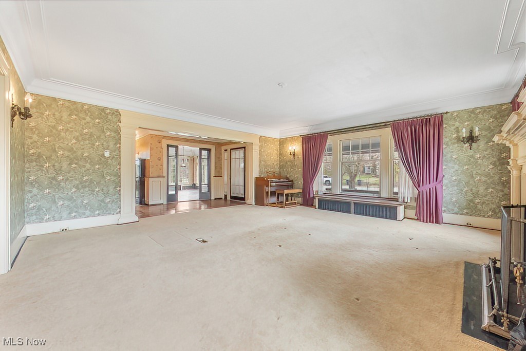 245 Merriman Road Akron, OH 44303 - Photo 16 of 49 Unfurnished living room featuring radiator, wallpapered walls, crown molding, and carpet floors
