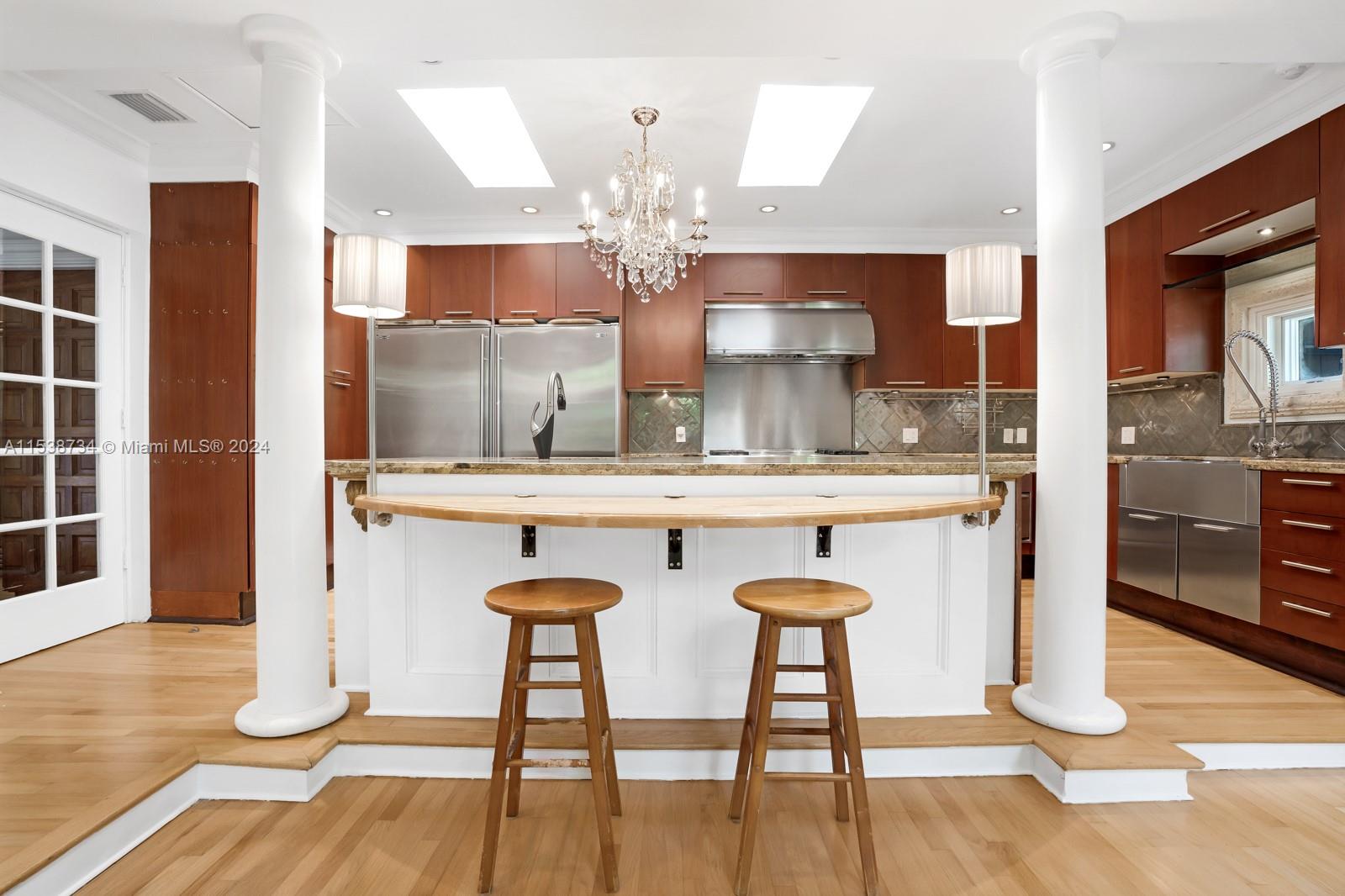 3685 Royal Palm Avenue Miami, FL 33133 - Photo 14 of 41 a kitchen with stainless steel appliances kitchen island a chandelier and wooden cabinets