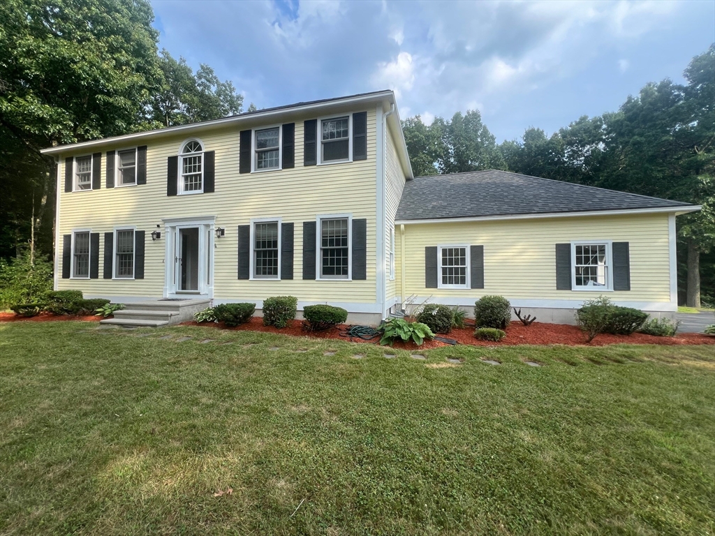a front view of a house with a garden and trees