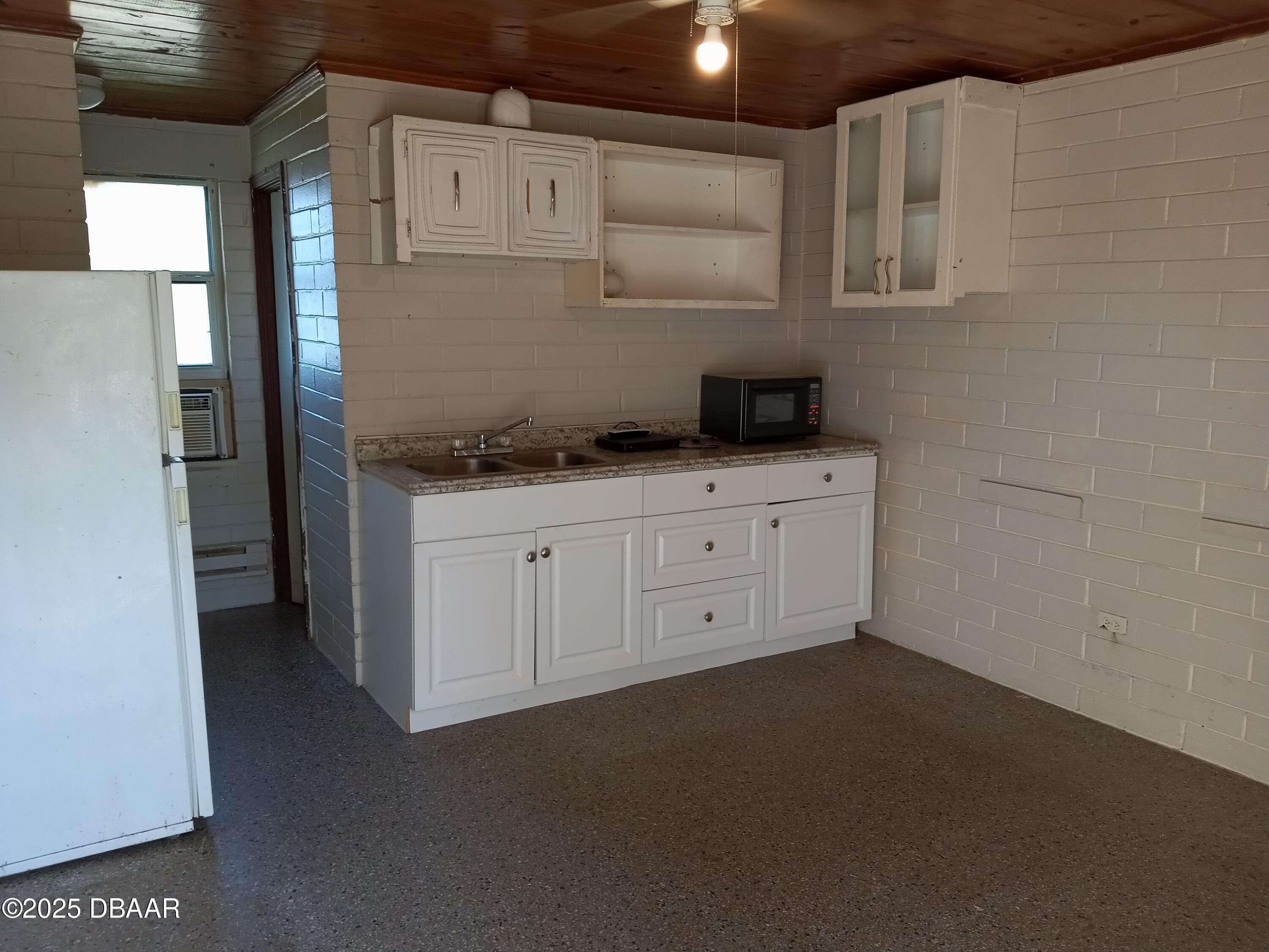 703 South Ridgewood Avenue, Unit 10 Edgewater, FL 32132 - Photo 3 of 5 a kitchen with white cabinets a sink a stove and a refrigerator