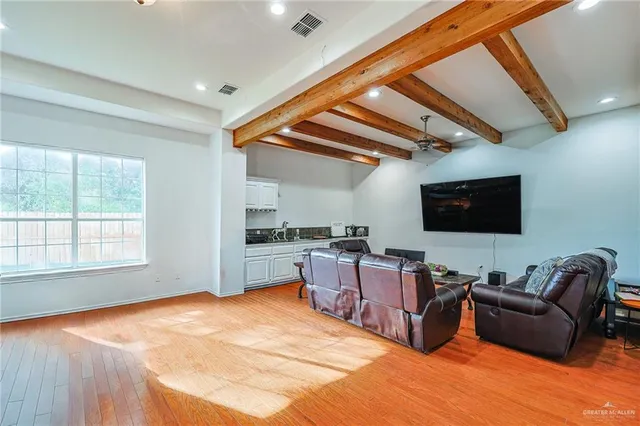 a living room with furniture a flat screen tv and kitchen view