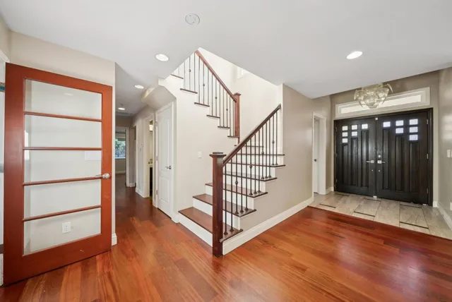 a view of an empty room with wooden floor and windows