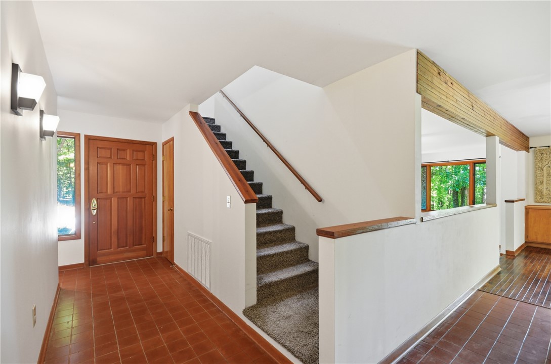 1298 Carradine Road Seneca, SC 29678 - Photo 25 of 43 A welcoming entry features a stunning wood door, terra cotta flooring, and a carpeted staircase leading to upper levels.