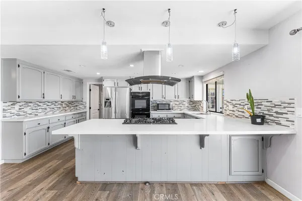 a large kitchen with kitchen island a stove a sink a center island and wooden floor