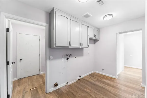 a view of a kitchen with white cabinets and wooden floor