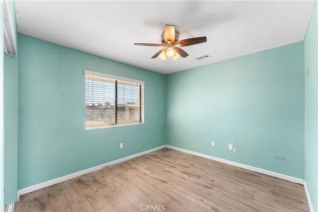 an empty room with wooden floor fan and windows