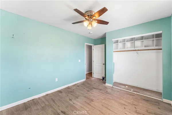 an empty room with wooden floor and ceiling fan