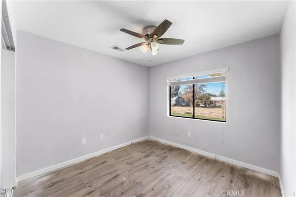 an empty room with window and ceiling fan